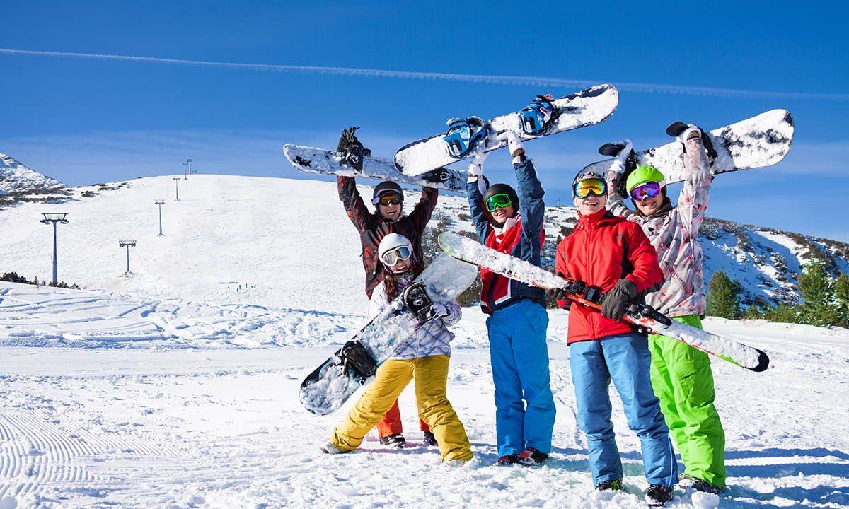 Five snowboarders holding boards and skies together