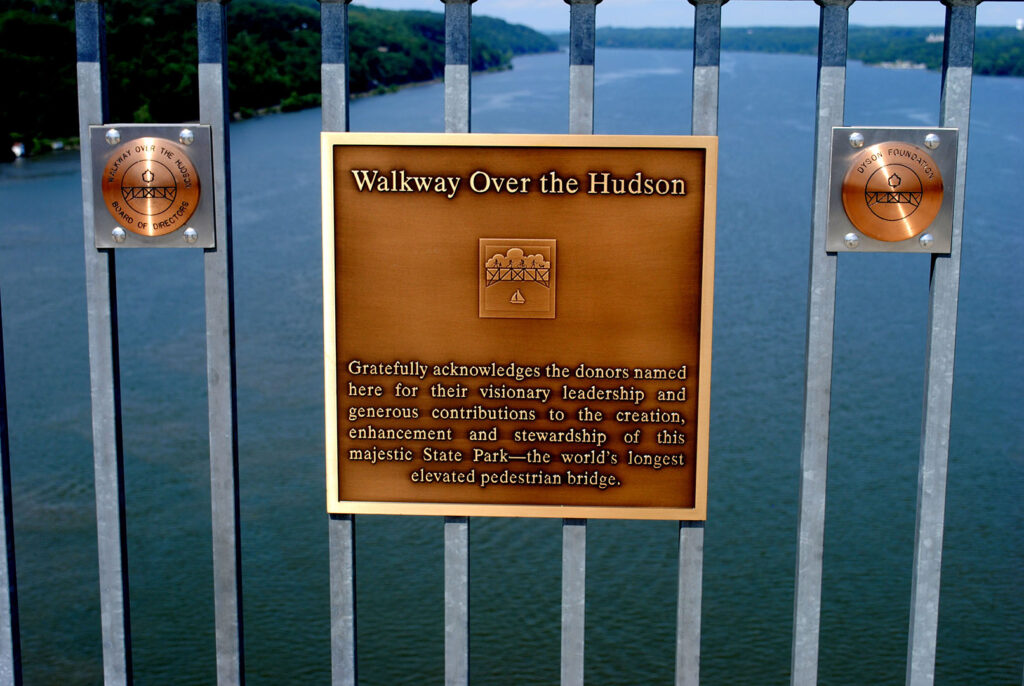 Historic Plaque on the Walkway Over the Hudson Bridge - Hudson Valley Luxury Resorts Close-up of a bronze plaque on the Walkway Over the Hudson railing, recognizing donors and contributors to the historic bridge’s renovation.