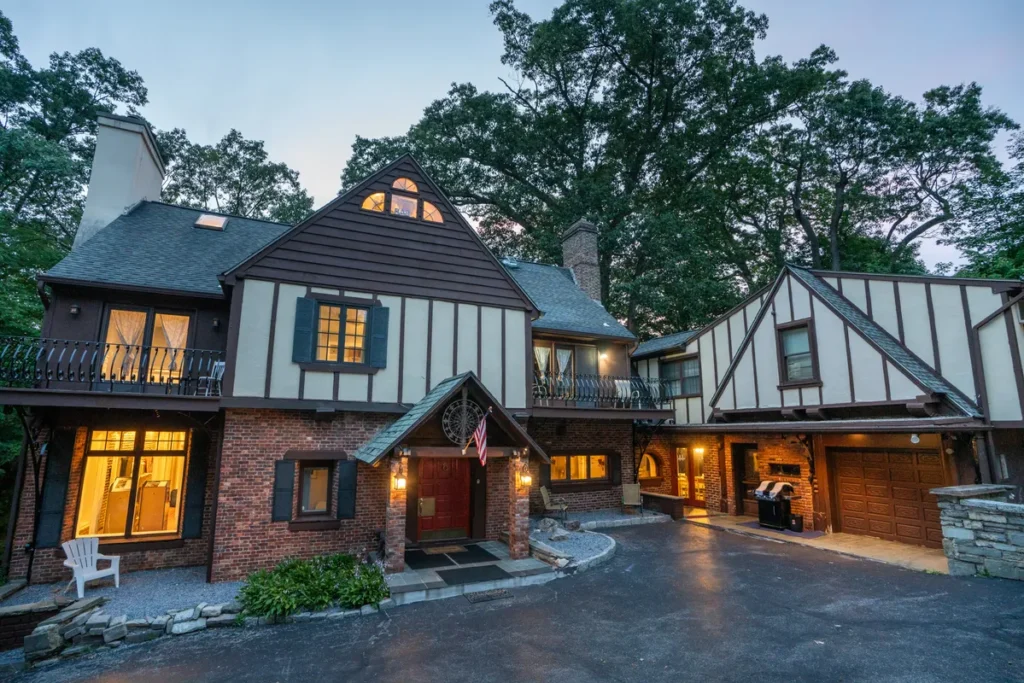 Tudor-style luxury resort estate with brick facade, timber framing, and outdoor fireplace in Hudson Valley